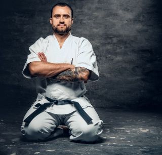 studio portrait bearded brutal karate fighter dressed white kimono grey background (1) (1)